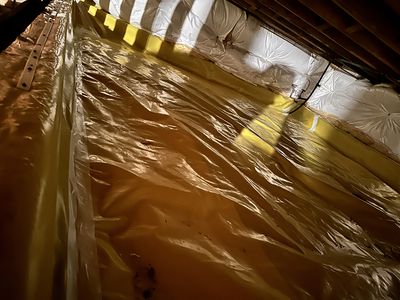 Crawl space set up with yellow and white moisture barriers from a different angle