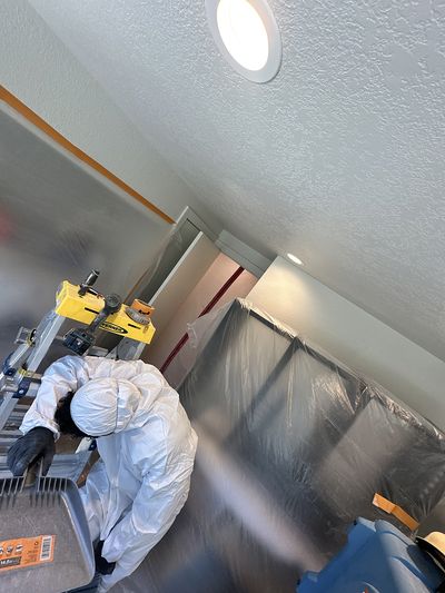 Water damage restoration technician working in a recently restored room with moisture barriers set up
