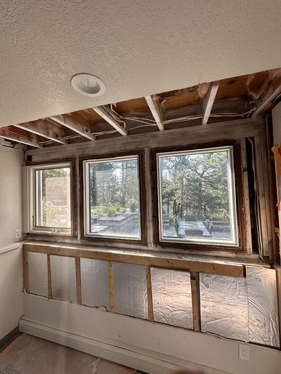 Room on first floor facing back garden with water-damaged wall and ceiling panels removed