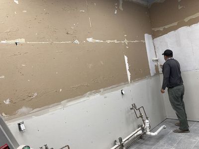 declare it restored & remodeled crew member applying primer to commercial building wall