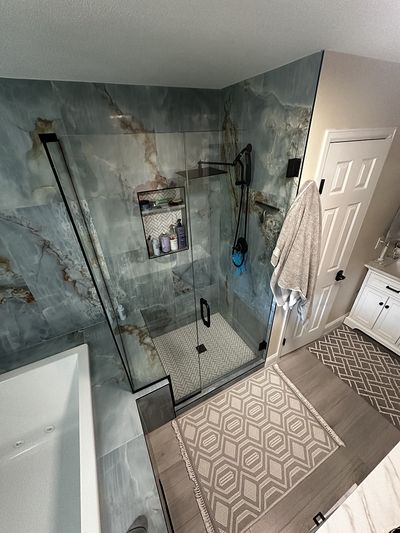 Glass shower stall in a newly remodeled bathroom with marble wall tiling