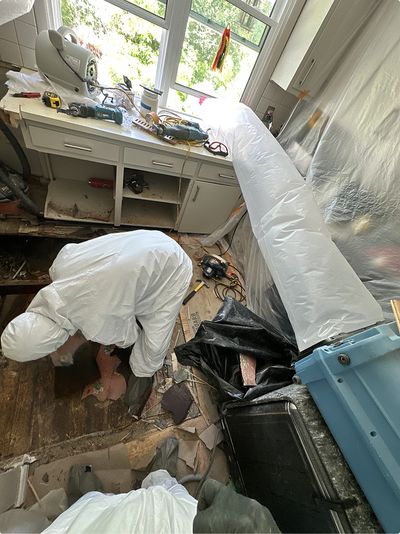 declare it restored & remodeled technician removing water-damaged and moldy floorboards